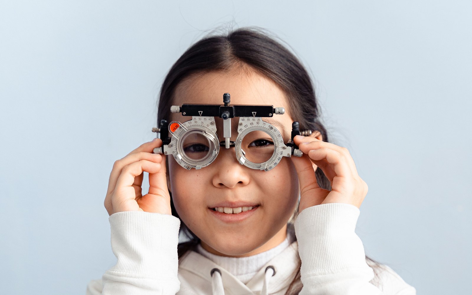 Petite fille souriante portant une lunette d'essai lors d'un contrôle de la vue