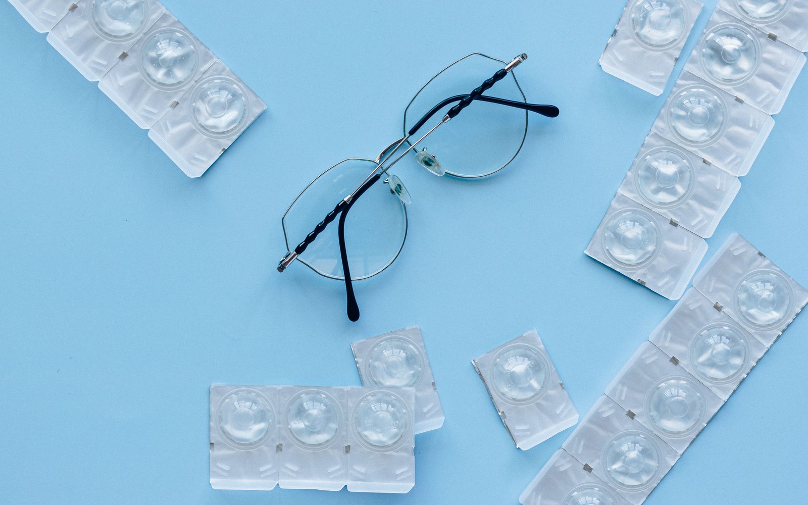 Lunettes de vue entourées de lentilles de contact en blister